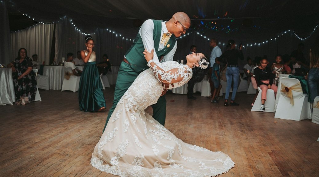 man in black suit jacket holding woman in white wedding dress