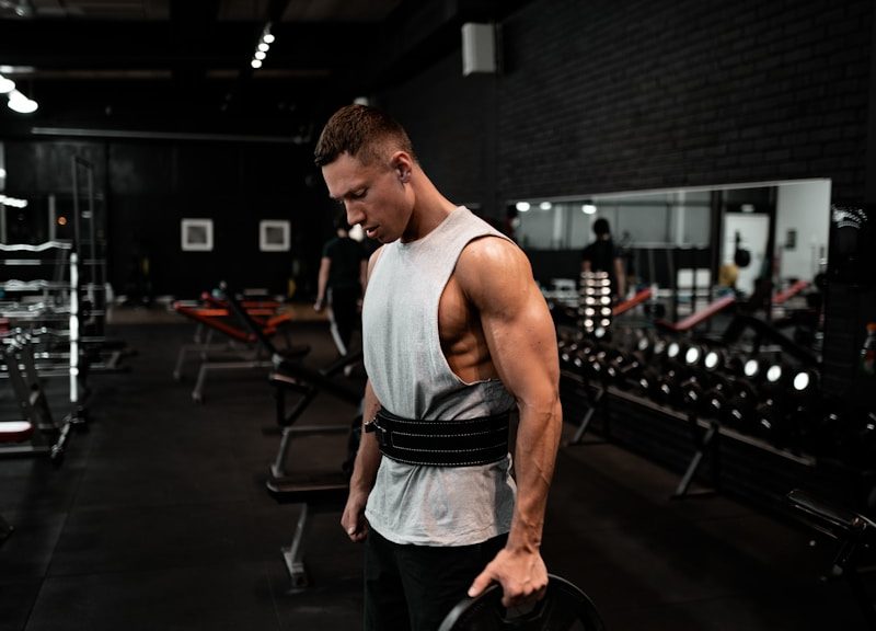 man in white tank top holding bumper plate